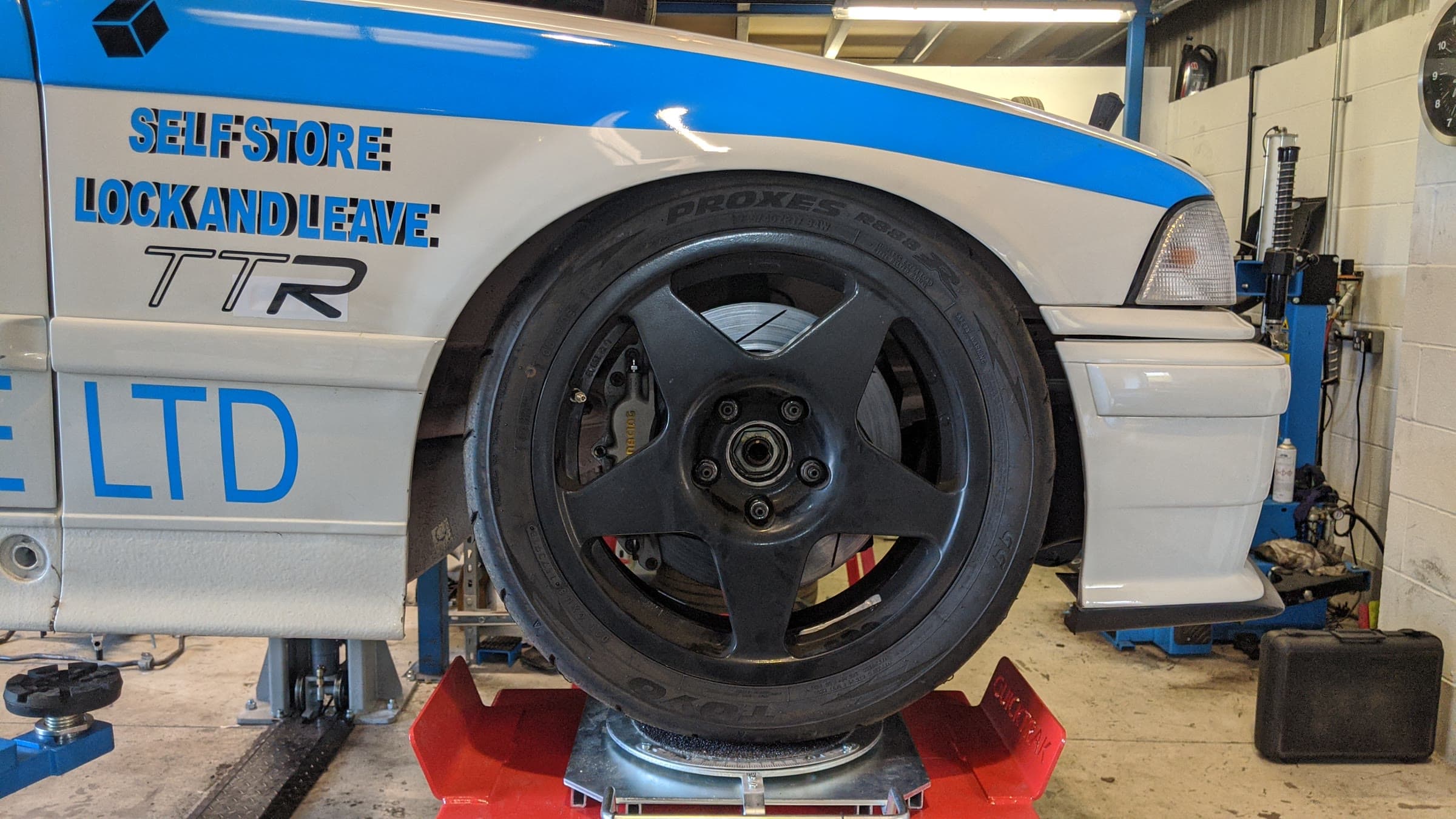 A white and blue TTR race car on the alignment turntable