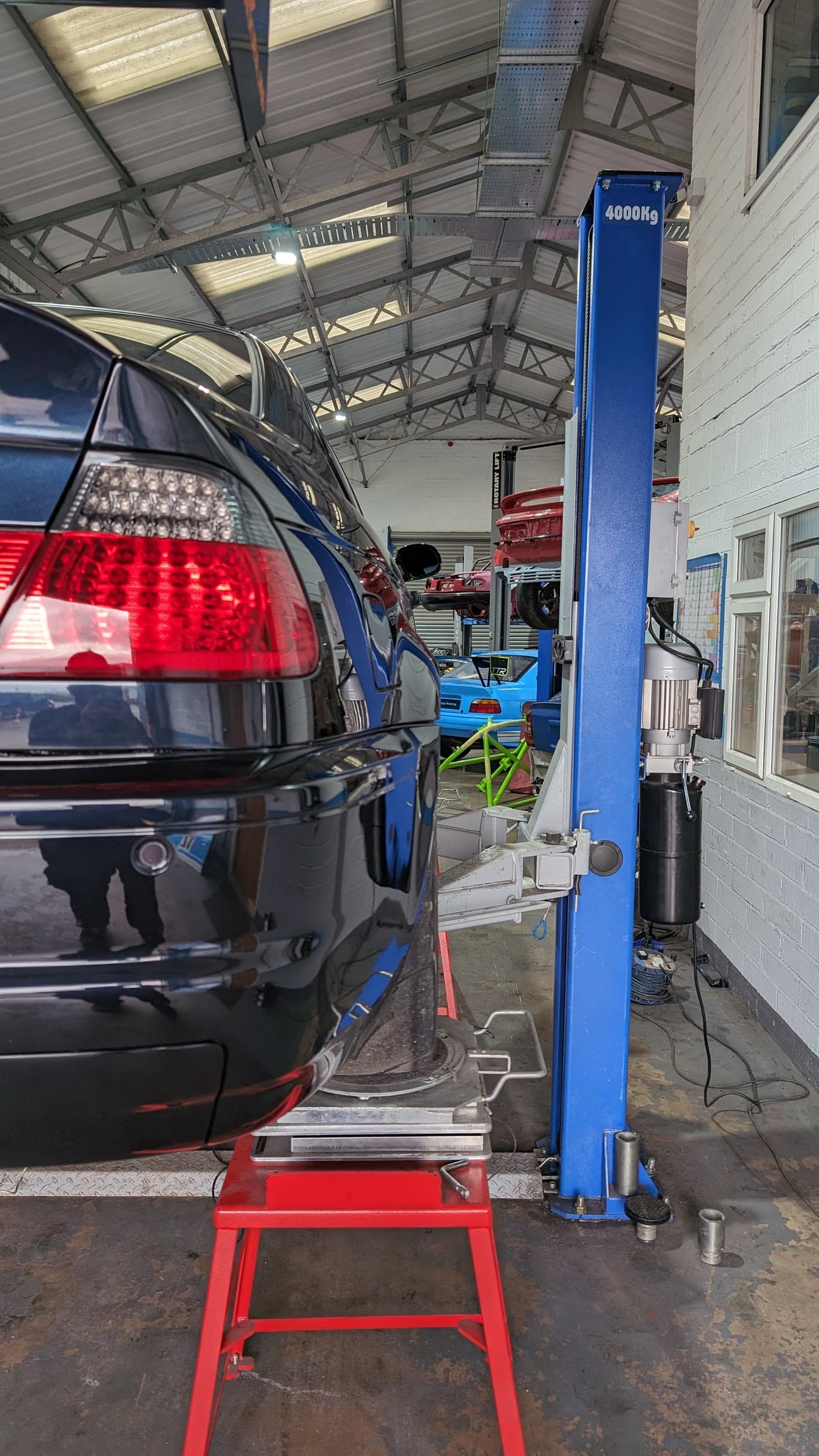 A black BMW E46 on the TTR alignment rig, wheels on the turntables