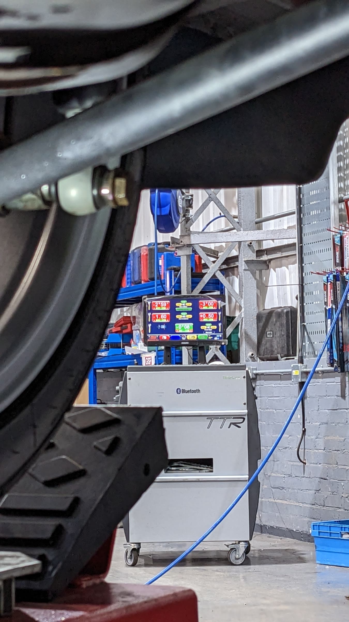 The TTR alignment console showing live camber and toe readings, seen from under the car