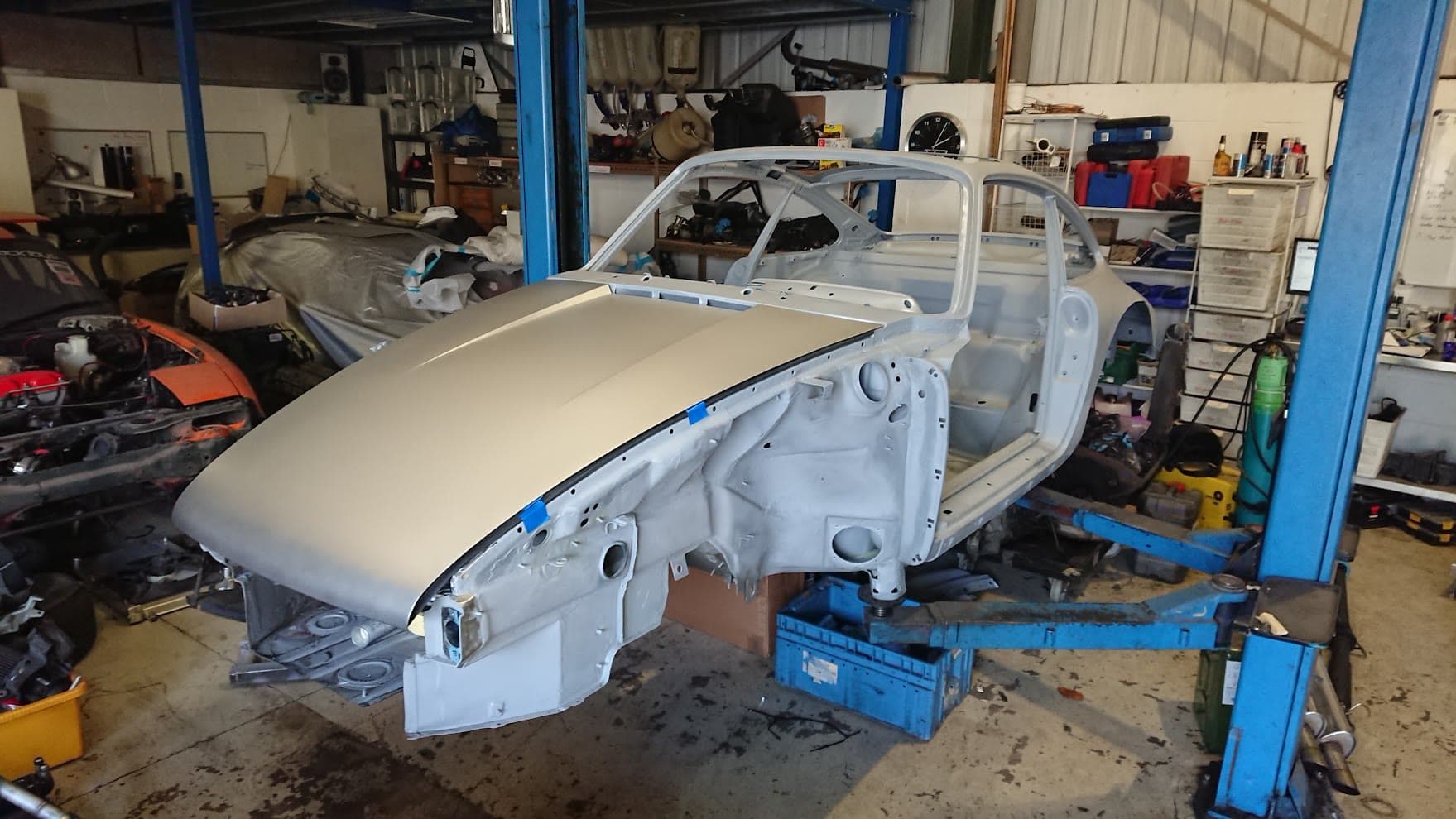A Porsche 911 bodyshell in primer on a lift