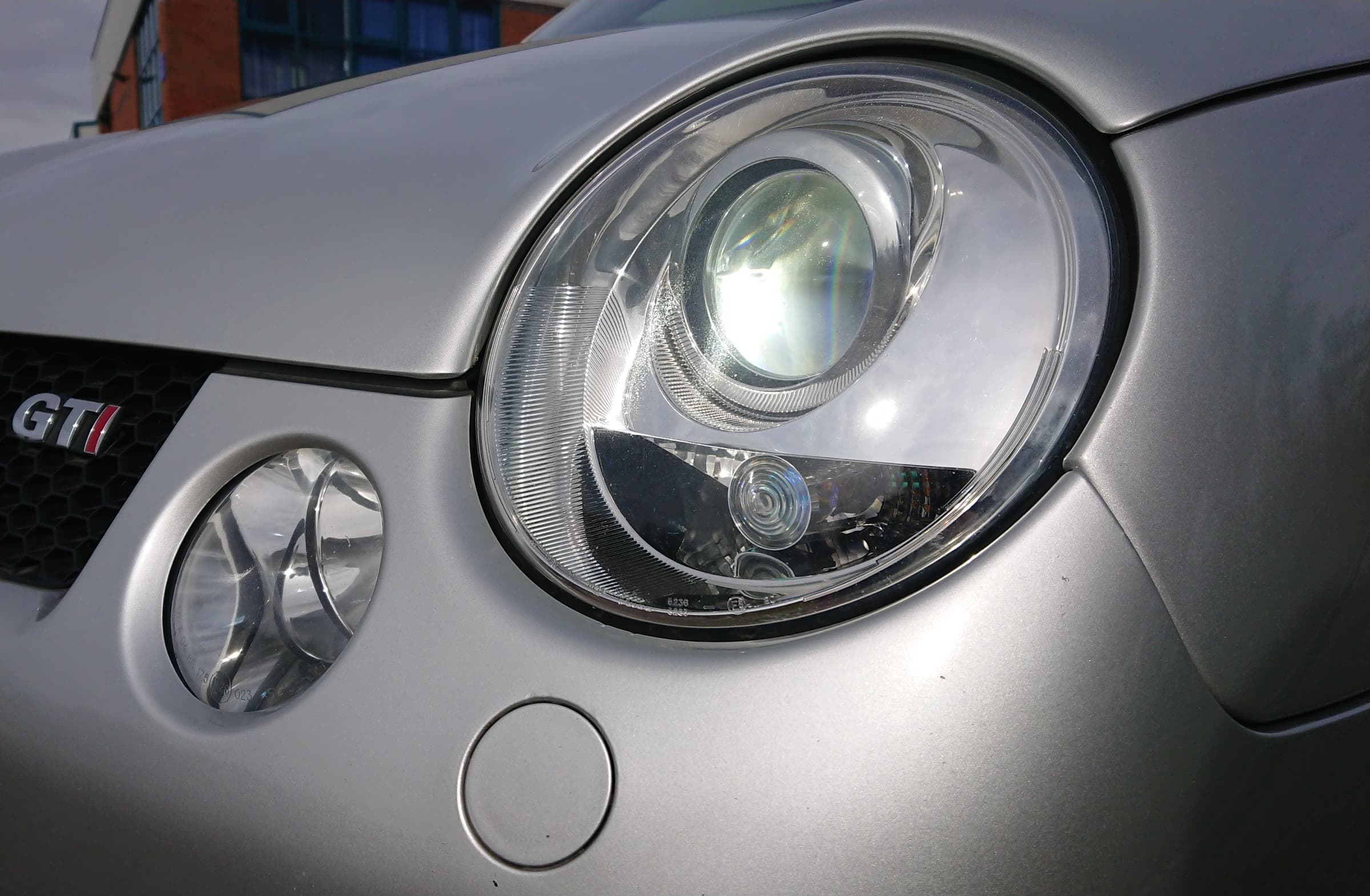 The headlight of a silver VW Lupo GTI