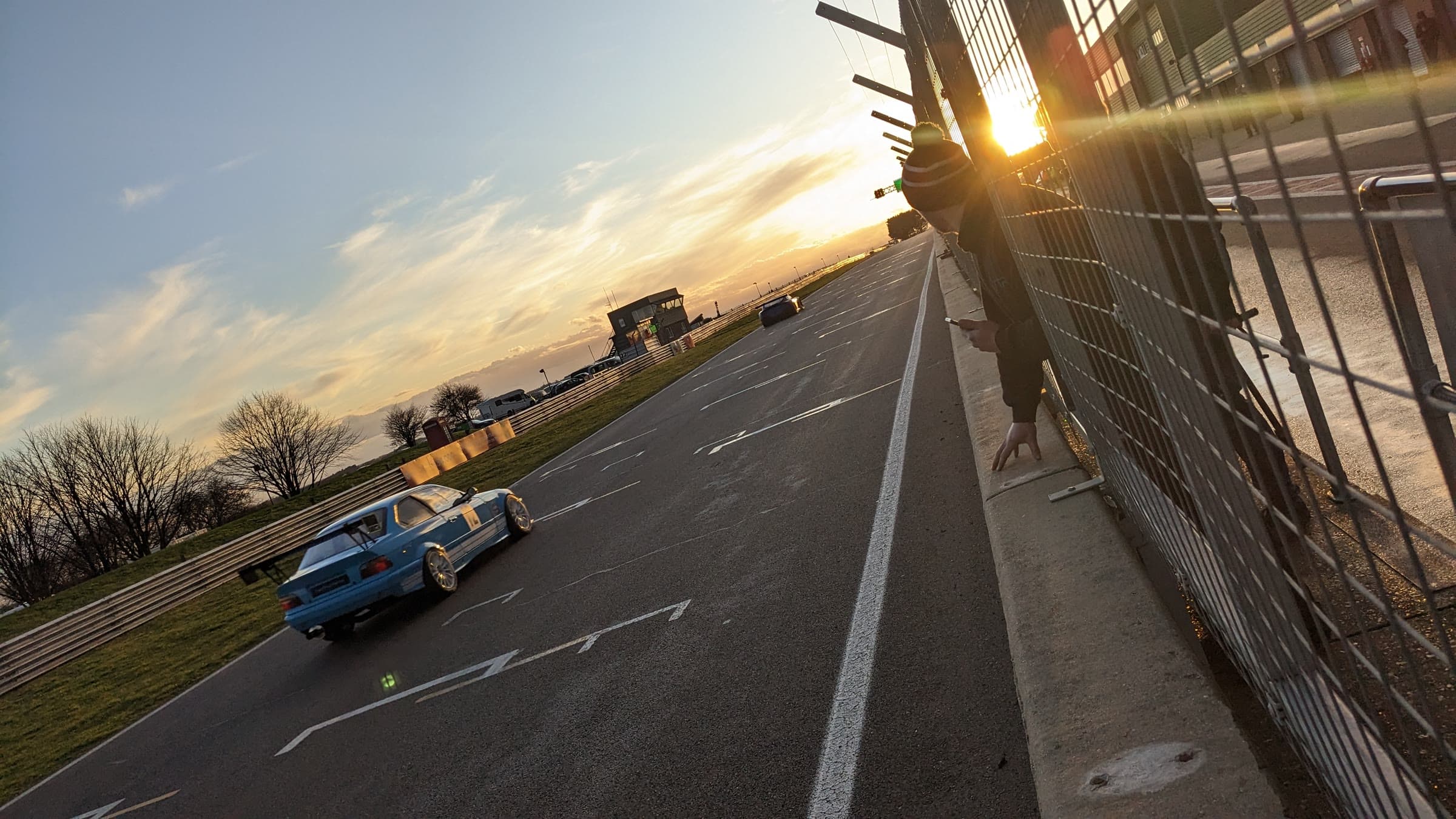A car on track at sunset, seen from the pit wall
